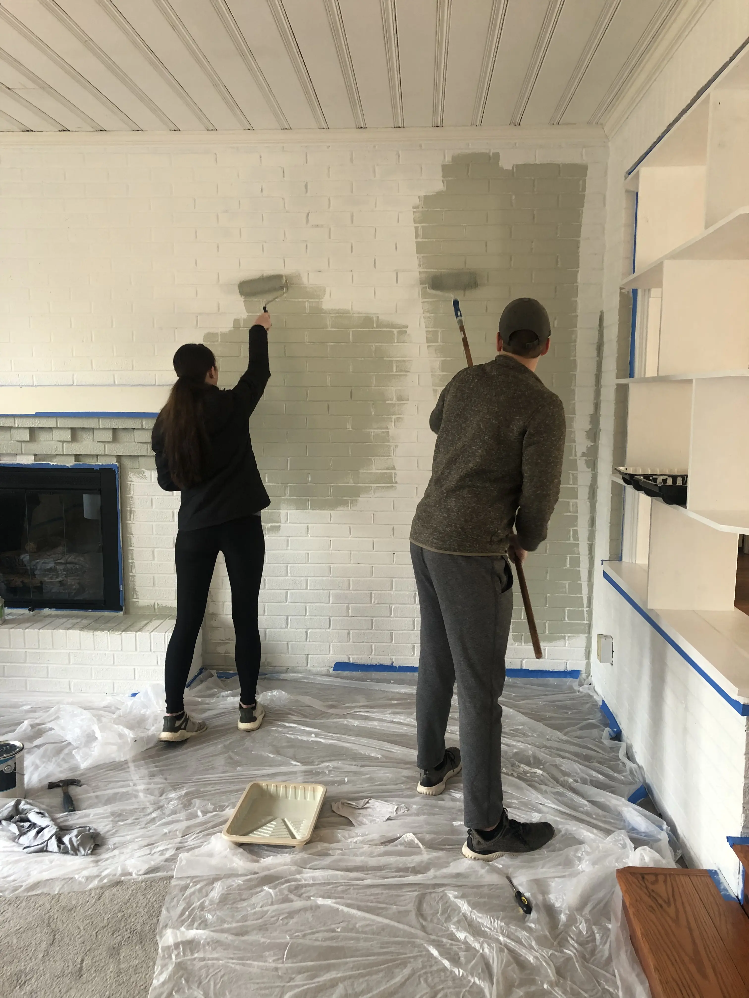 Martie and holden painting brick wall in the living room